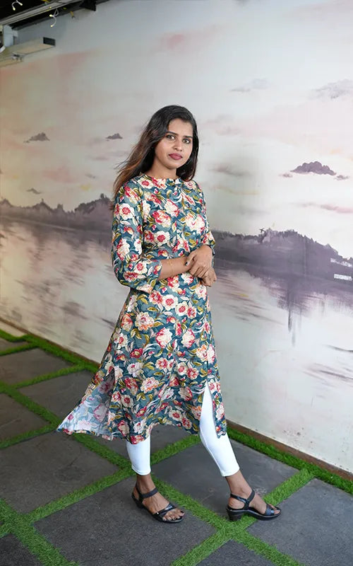 A-line princess cut rayon kurti with side pockets with floral design on a bluish green base.